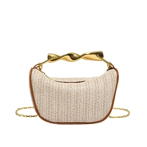 Détail du sac en paille tissée avec bordure en cuir marron et poignée en métal doré