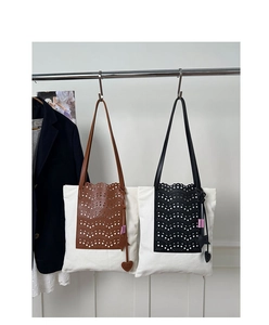 Detail of laser-cut wave leather on canvas bucket bag with heart and star charms
