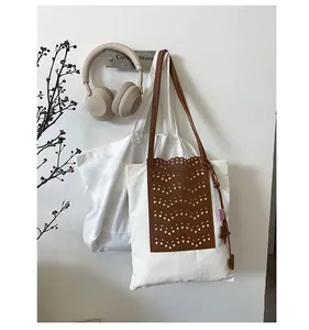 Detail of canvas bucket bag with brown hollowed-out leather overlay and star pendant