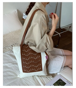 Detailed view of canvas tote bag with brown laser-cut leather and woven pink label