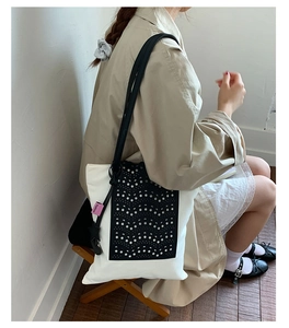 Detail of laser-cut black hollow pattern and pink fashion label on canvas tote bag