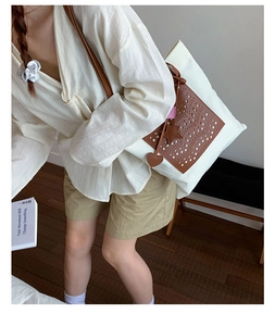 Detail of canvas tote bag with brown leather patchwork and hollow-out circular pattern