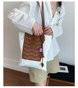 Detail of canvas tote bag with laser-cut brown leather waves and star-shaped charm