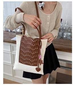 Detail of canvas tote bag with brown laser-cut leather inlay and star heart charms