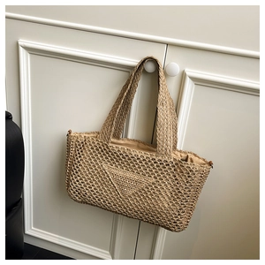 Detail einer handgewebten Stroh-Tote-Bag mit Dreiecksmuster an einem weißen Schrank hängend