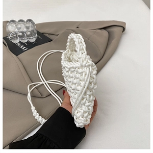 Close-up of white handmade woven mini bag with intricate diamond patterns and shoulder strap