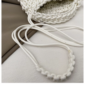 Close-up of white hand-woven crossbody bag showing textured knit patterns and rope strap