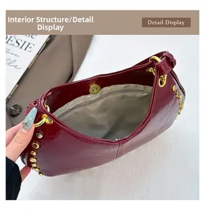 Internal view of burgundy patent leather handbag featuring gold rivets and zipper pocket