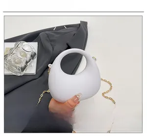 Detail of white semi-circle acrylic handbag with elegant gold metal chain strap