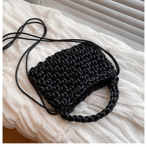 Detailed macro view of black woven texture and circular handle on the crossbody bag