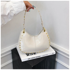 Detailed close-up of cream hobo bag with polished golden rivets and sleek stitching