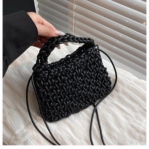 Detail of handwoven black crossbody bag with integrated handle in artistic shadow lighting