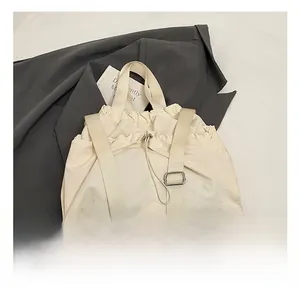 Detail view of cream nylon tote bag featuring drawstring closure and pleated design
