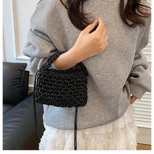 Detail shot of black woven handbag featuring high-density leather texture and thick handle