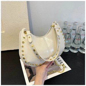Detail of white crescent bag with gold metal studs and glossy leather finish