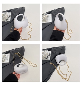 Detail view of white minimalist egg-shaped acrylic bag with gold chain strap