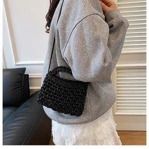 Detail of hand-woven black crossbody bag showing textured cord weave and leather strap
