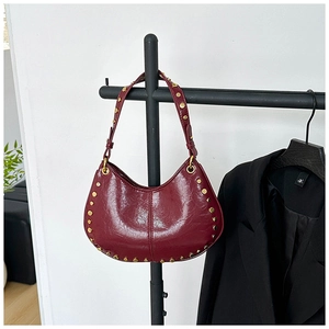 Detail of burgundy leather shoulder bag with gold studs on a black metal hanger