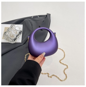Close-up of minimalist purple acrylic bag with golden chain and round hollow handle