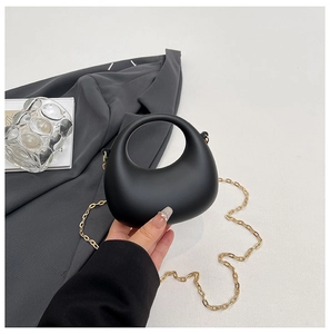 Detail of black crescent handbag with gold chain strap and ring handle design