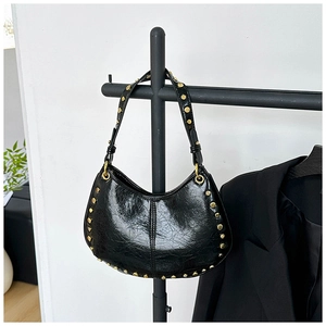 Detail of glossy black hobo bag featuring golden rivets and premium wrinkled texture