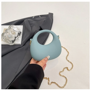 Detail of light blue crescent bag with circular handle and gold chain strap
