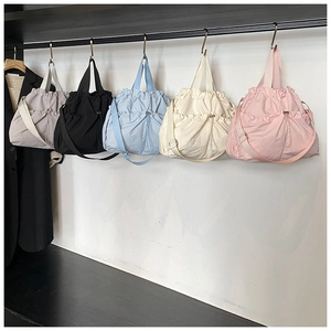 Detail view of drawstring nylon tote bags in five colors with adjustable shoulder straps