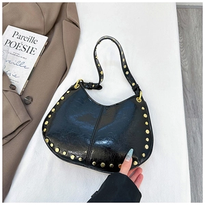 Close-up of black rivet handbag with glossy wrinkled texture and gold hardware details