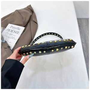 Detail of black glossy leather bag with gold rivet studs and side stitching craftsmanship