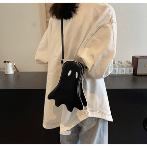 Close-up of a black ghost-shaped crossbody bag with white embroidery and strap detail