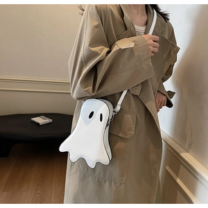 Ghost-shaped white crossbody bag styled with a brown trench coat in a cozy setting