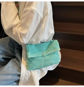 Détail du sac bandoulière en denim délavé bleu lac avec bouton en métal sur modèle