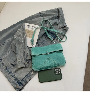 Vue à plat du sac messager en denim vert lac avec bandoulière réglable et couture triangle