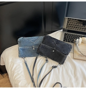 Détail de sacs bandoulière en denim délavé gris et bleu avec boutons en métal sur un lit blanc