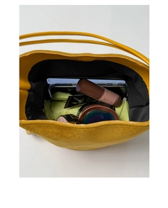 Interior view showing the large capacity and storage of the yellow suede bucket bag