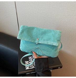 Detail of mint green denim crossbody bag showing silver hardware and stitching texture