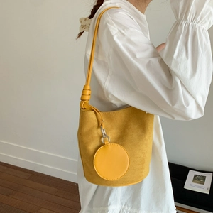 Detail of yellow matte shoulder bucket bag with a round hanging purse on the strap