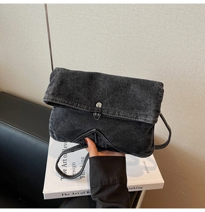 Detail of a vintage black denim crossbody bag featuring a silver metal buckle closure