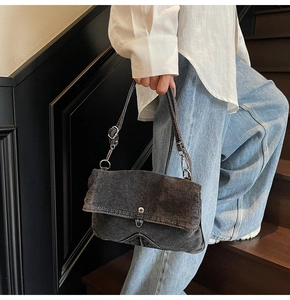 Texture détaillée du sac messager en denim délavé gris foncé avec bandoulière et bouton métal
