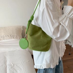 Detail of sage green matte bucket bag featuring a knot-strap and small circular charm