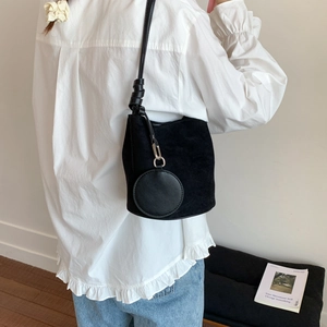 Detailed close-up of a black matte suede bucket bag with round coin purse accessory