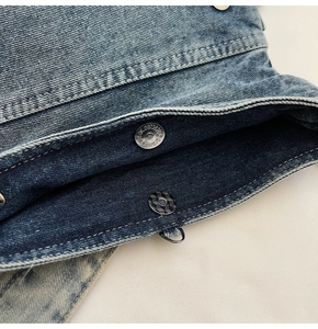 Macro du fermoir magnétique en métal et texture denim bleu délavé sur le sac besace