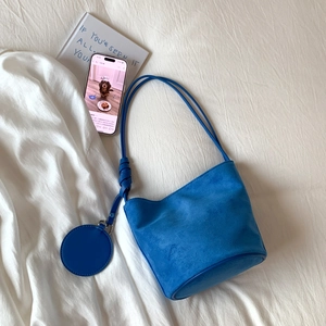 Detailed view of royal blue frosted suede bucket bag with knotted shoulder strap and round pouch