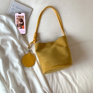 Detail of ginger matte leather bucket bag with circular coin pouch and knot strap