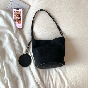 Detail of black matte suede bucket bag with shoulder strap and round coin purse attachment