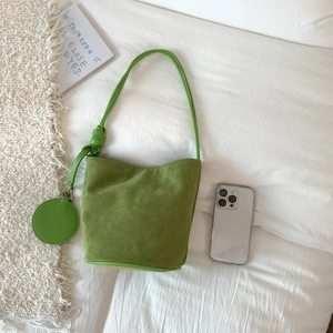 Close-up of grass green suede bucket bag with matching mini pouch and knotted strap detail
