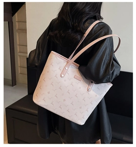Detail of light pink monogram tote bag with deer pattern held by a model in black leather