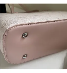 Detail shot of the pink tote bag featuring protective metal feet and precise stitching