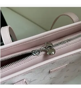 Detail of smooth silver metal zipper on pink leather tote bag with embossed pattern