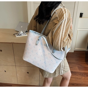 Close-up of white tote bag with blue and pink deer print and light blue leather handles